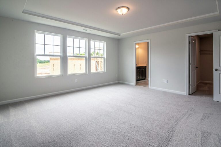 Bright and empty room with large windows and carpet flooring, suitable for interior design.